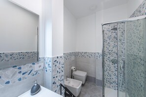 A modern bathroom with a glass shower enclosure, a white sink, and a toilet.