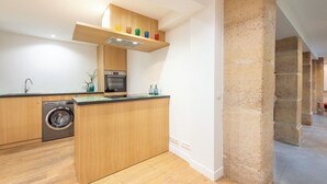 Une cuisine compacte avec des meubles de rangement en bois, un lave-linge encastré et un petit plan de travail.