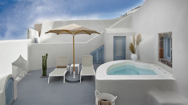 Une terrasse extérieure moderne dotée d’un jacuzzi, de chaises longues et d’un parasol décoratif.