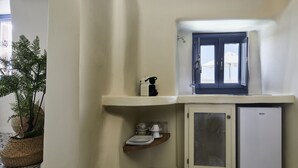 Une petite cuisine équipée comprenant un réfrigérateur, une fenêtre avec vue et une étagère contenant des ustensiles de cuisine.