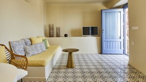 Une pièce comprenant un canapé, une petite table, un téléviseur fixé au mur et un sol à motifs.