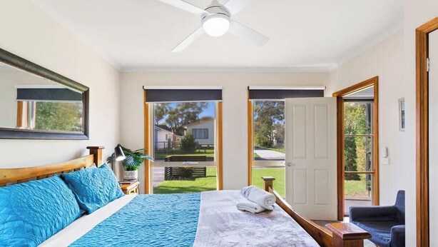 Un dormitorio con cama, mesita de noche, silla y ventilador de techo.