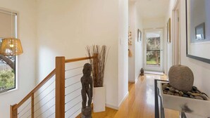 A modern interior with a wooden staircase, a sculpture, and a stone centerpiece. - Serene, Modern Beach Escape 3 Bed 2 Bath (Cape Woolamai)