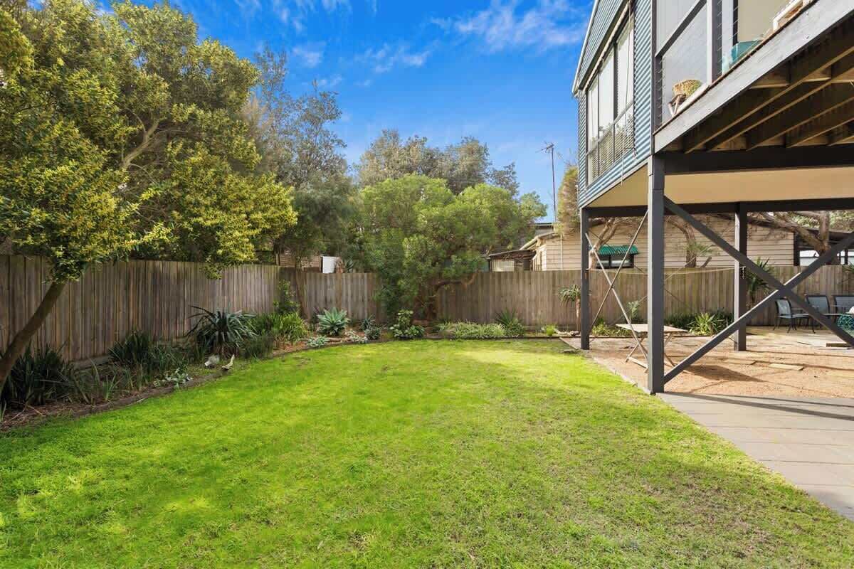 A backyard with a wooden deck, a grassy lawn, and a wooden fence.