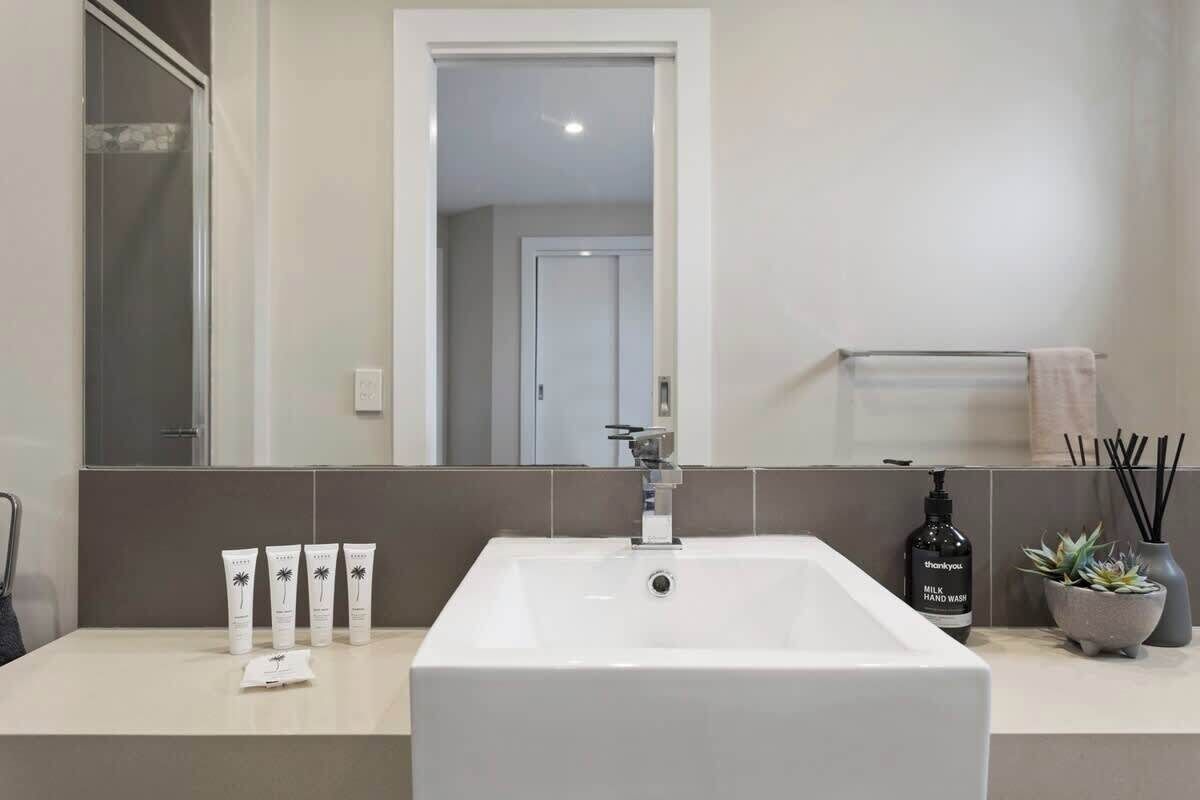 A bathroom with a white sink, a mirror, a towel rack, and a small potted plant.