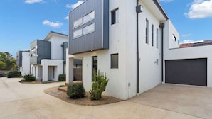 Un immeuble résidentiel moderne doté d’un toit plat, d’un garage et d’une allée bien entretenue.