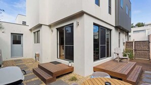 Une maison moderne dotée d’un patio, d’un abri pour voiture et d’une petite terrasse.