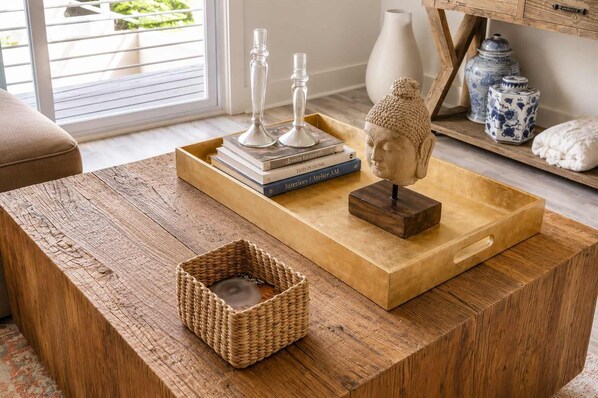 A wooden coffee table with a woven basket, a Buddha statue, and decorative vases.