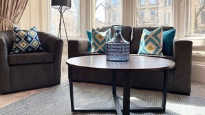 A modern living room with a dark sofa set, a round coffee table, and patterned cushions.