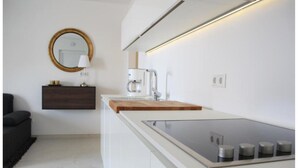 Una cocina moderna con estufa integrada, cafetera y tabla de cortar de madera.
