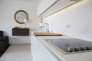 Une cuisine moderne équipée d’une cuisinière intégrée, d’une machine à café et d’une planche à découper en bois.