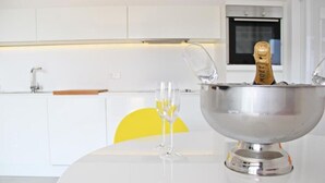 Una cocina moderna con encimera blanca, un bol de acero inoxidable y una botella de champán.