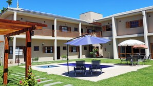 A two-story building with a swimming pool, outdoor seating, and a pergola. - Pousada das Bandeiras (Olímpia)