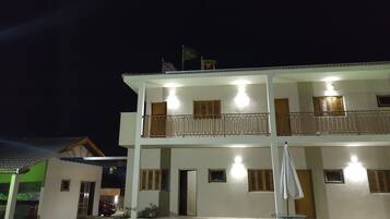 A two-story building with balconies, a flag, and a flagpole.