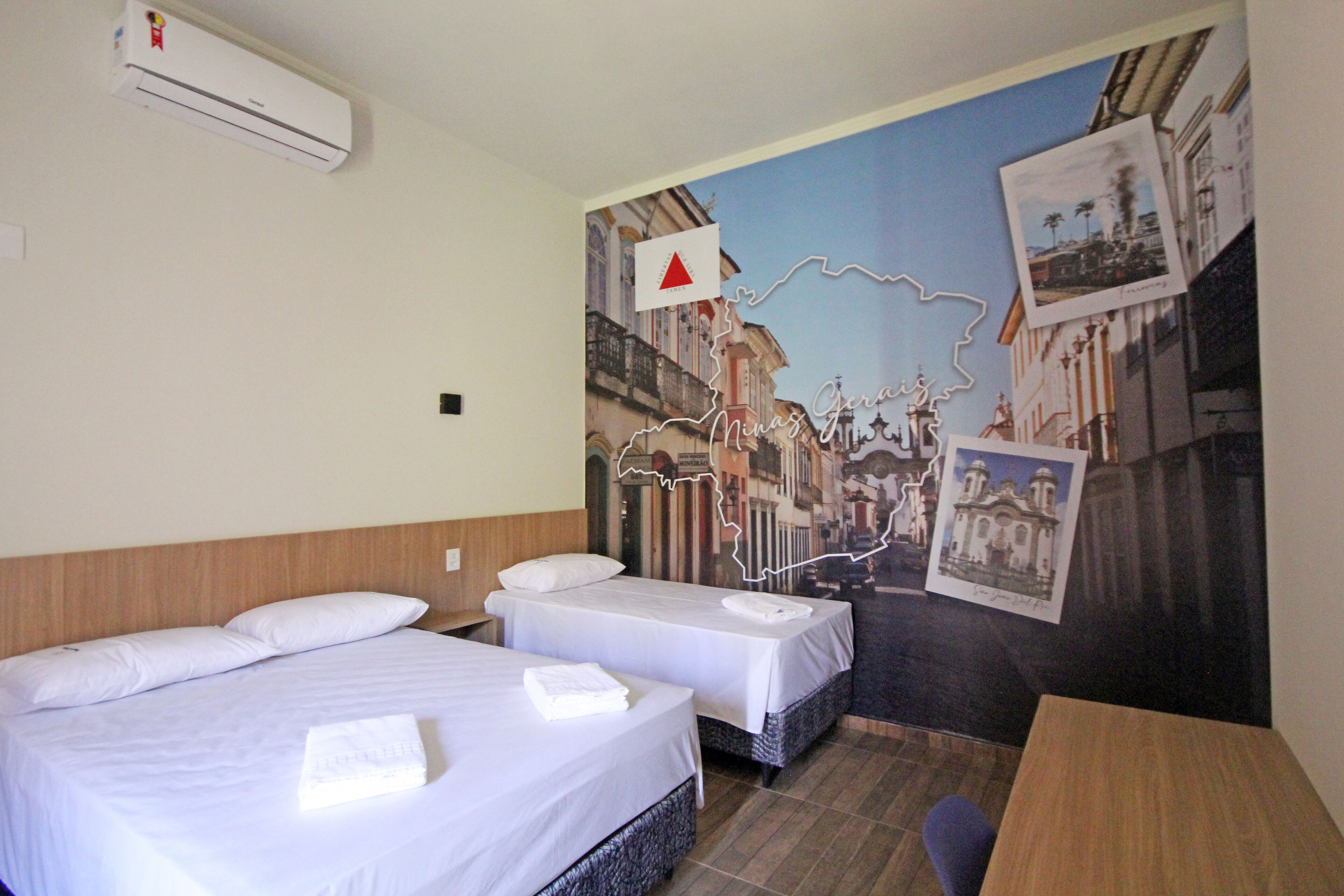 A hotel room with two beds, a wooden headboard, an air conditioning unit, and a mural of a cityscape.