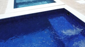 A rectangular hot tub with a tiled edge, surrounded by a tiled deck. - Pousada das Bandeiras (Olímpia)