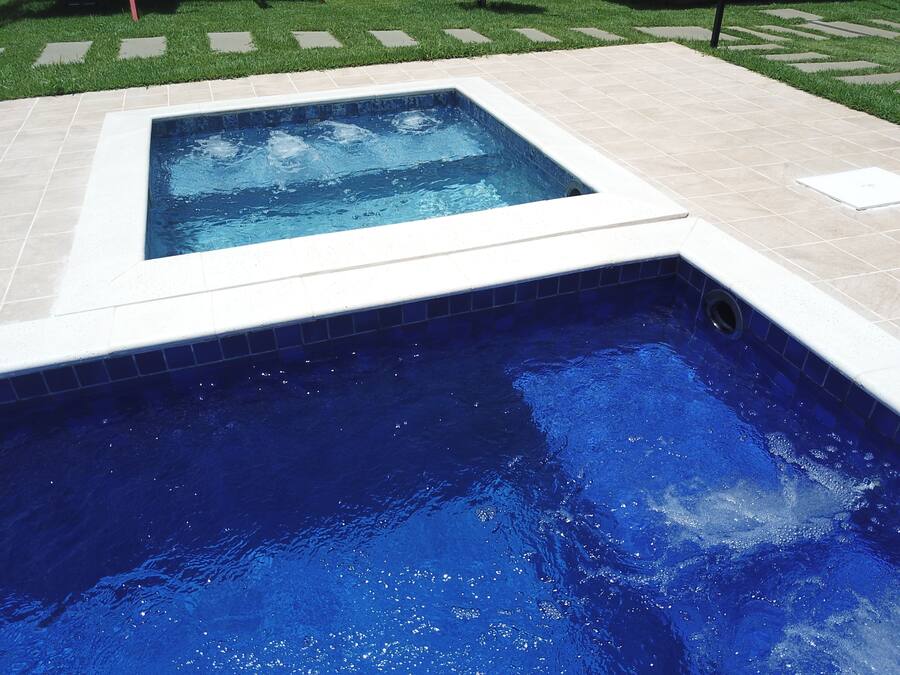 A rectangular hot tub with a tiled edge, surrounded by a tiled deck.