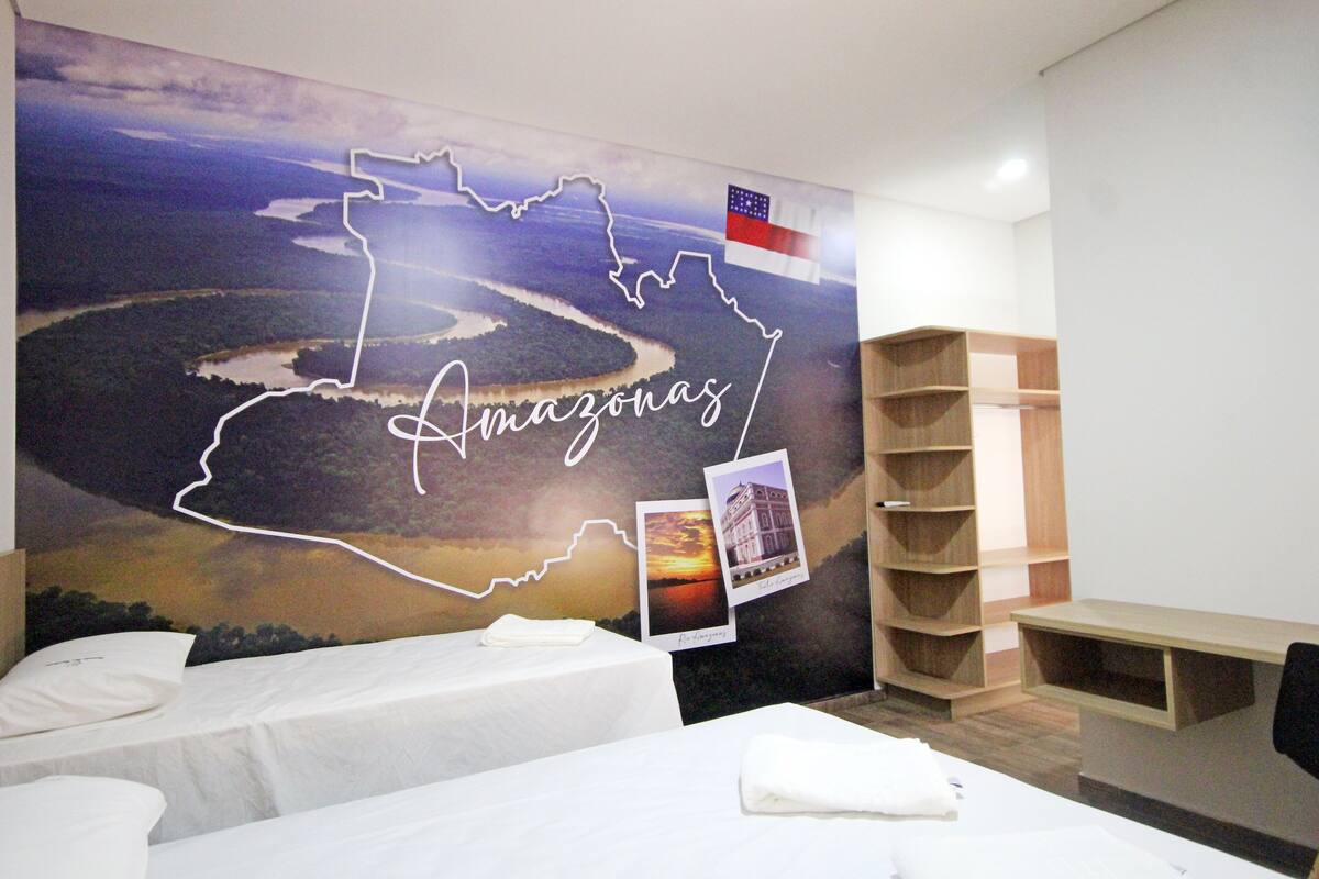 Ein Hotelzimmer mit einer großen Wandmalerei einer Flusslandschaft, einem Bett, einem Schreibtisch und einem Bücherregal.