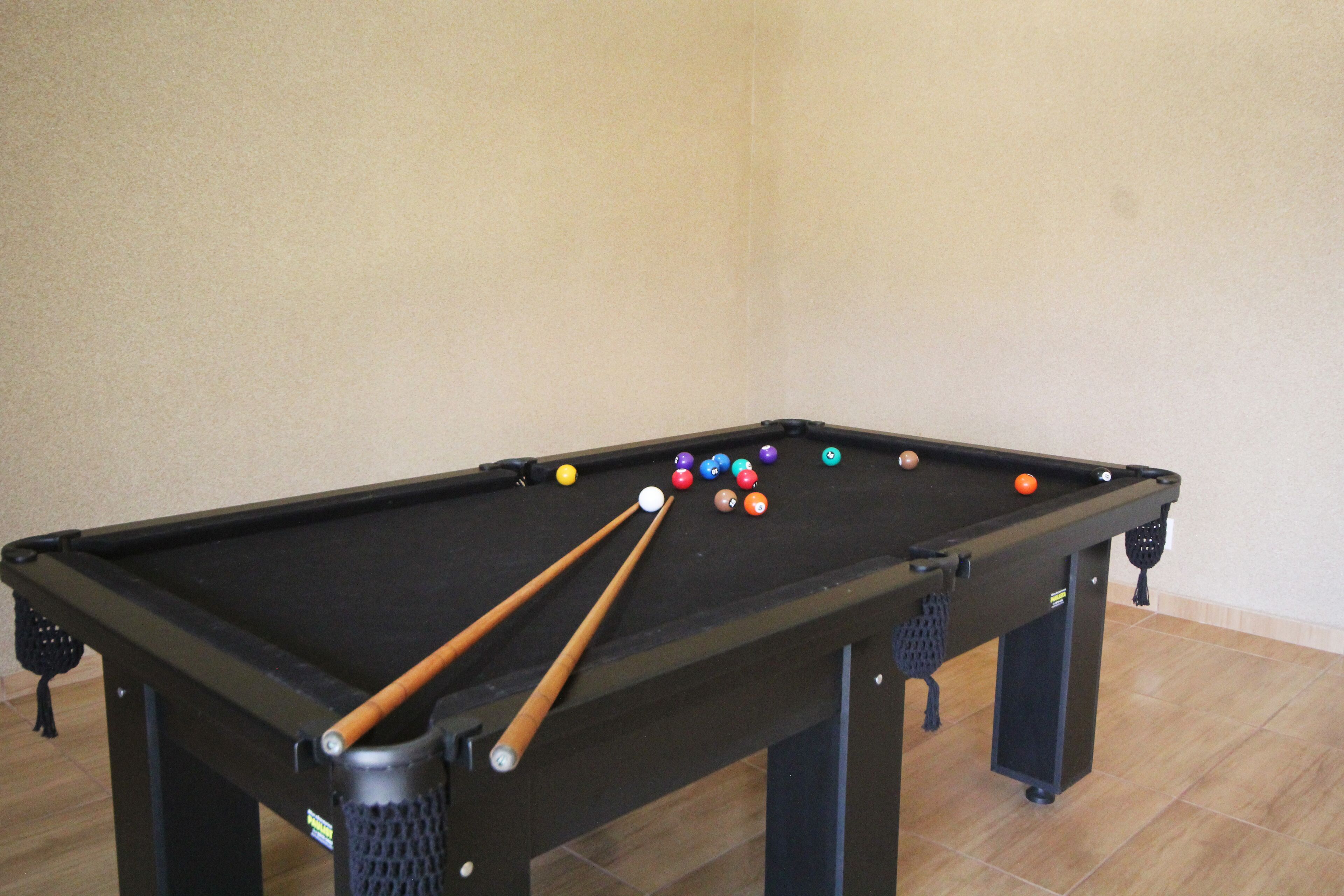 Une table de billard avec plusieurs billes et plusieurs queues de billard.