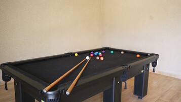 Une table de billard avec plusieurs billes et plusieurs queues de billard.