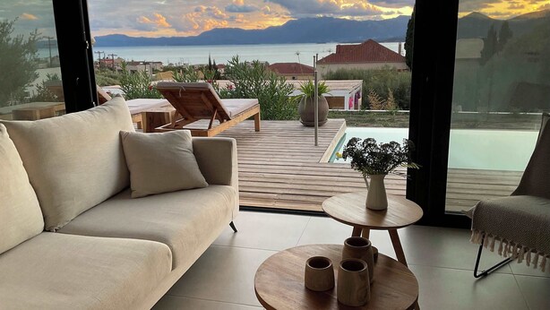Una sala de estar moderna con un sofá, una mesa de centro y vistas a una masa de agua y montañas.