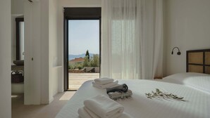 Un dormitorio con cama, vistas al exterior y un baño con toallero.