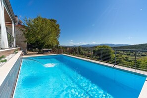 A swimming pool with a view of mountains and a tree.