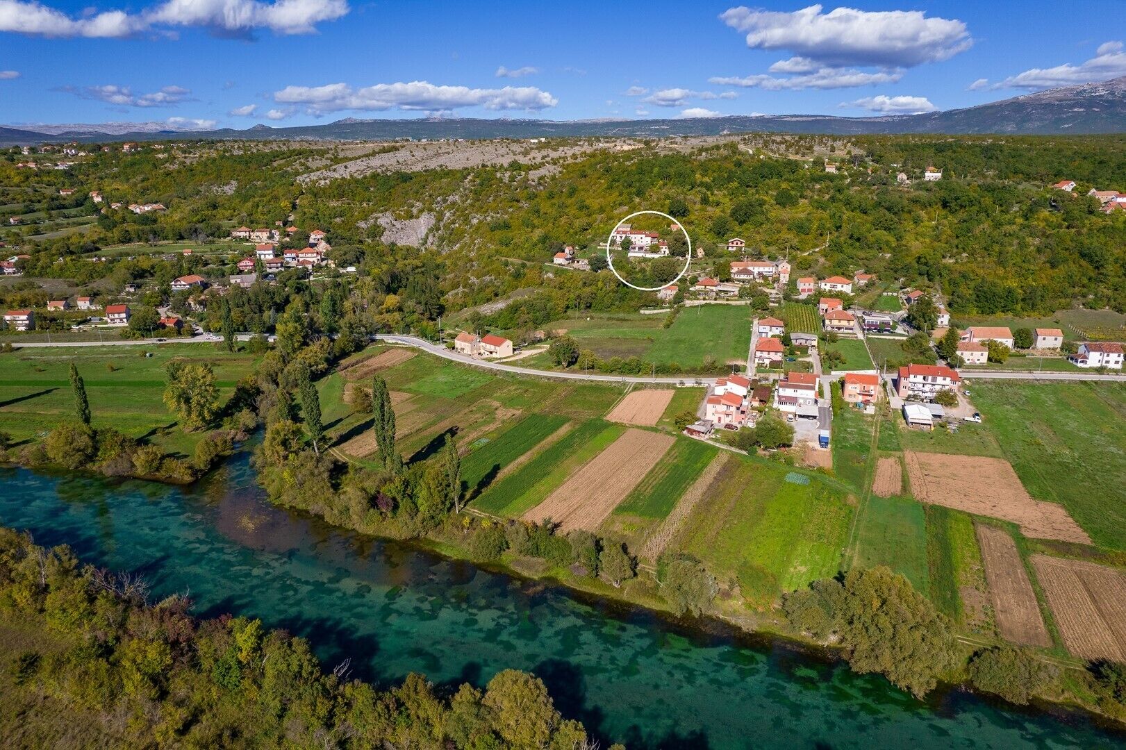 An aerial view of a rural area with houses, fields, and a river.