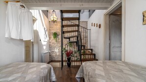 Un dormitorio con dos camas, una escalera y una pared de piedra.