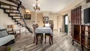 Un comedor con escalera de madera, candelabro y mesa con sillas.