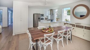 A modern kitchen with white cabinetry, a wooden dining table, and a large island with a built-in sink.
