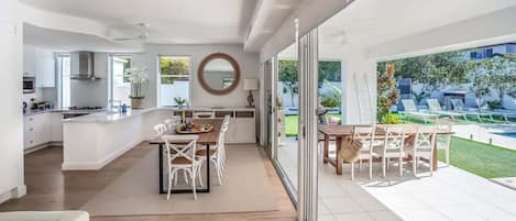 Una cucina moderna con zona pranzo, ampie finestre e vista su un giardino.