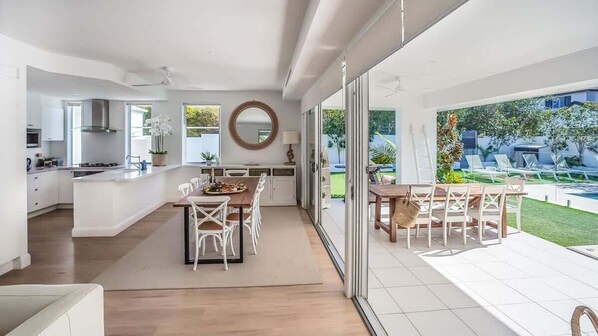 Une cuisine moderne avec un coin repas, de grandes fenêtres et une vue sur un jardin.