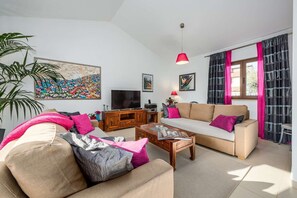 A living room with a sofa, coffee table, TV, and artwork on the wall.