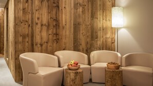 A modern living room with beige sofas, a wooden wall, and a floor lamp. - Naturhotel Waldheim (Anterivo)