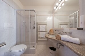 A modern bathroom with a glass-enclosed shower, a white toilet, a granite countertop, and a large mirror. - Naturhotel Waldheim (Anterivo)