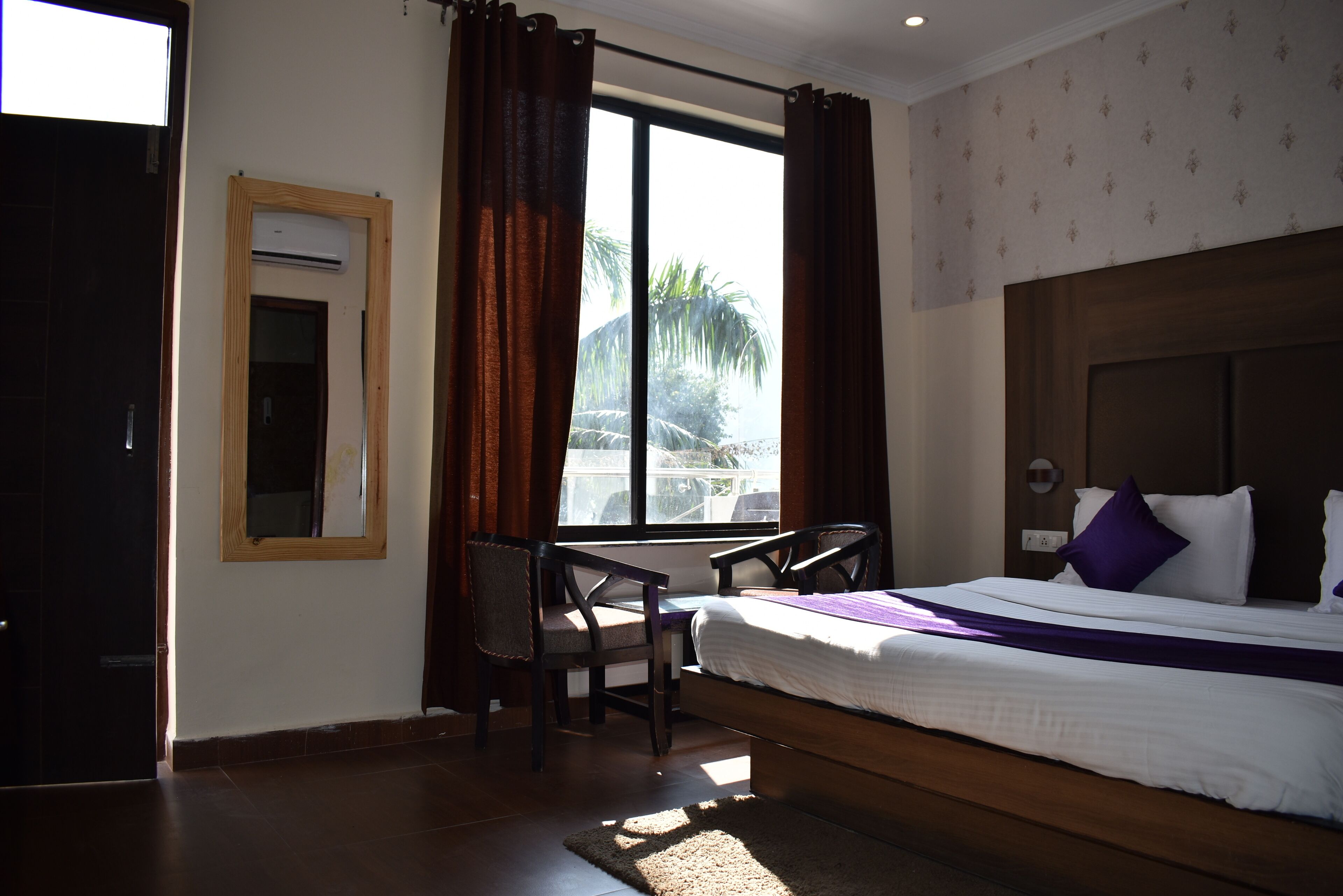 A hotel room with a bed, a desk, and a window with curtains.