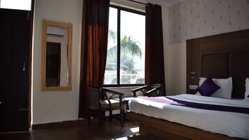 A hotel room with a bed, a desk, and a window with curtains.