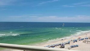 Una playa con sombrillas, gente, cielo despejado y el océano.