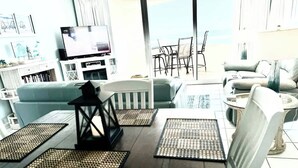 Un comedor con una mesa, sillas, un televisor y vistas al exterior.