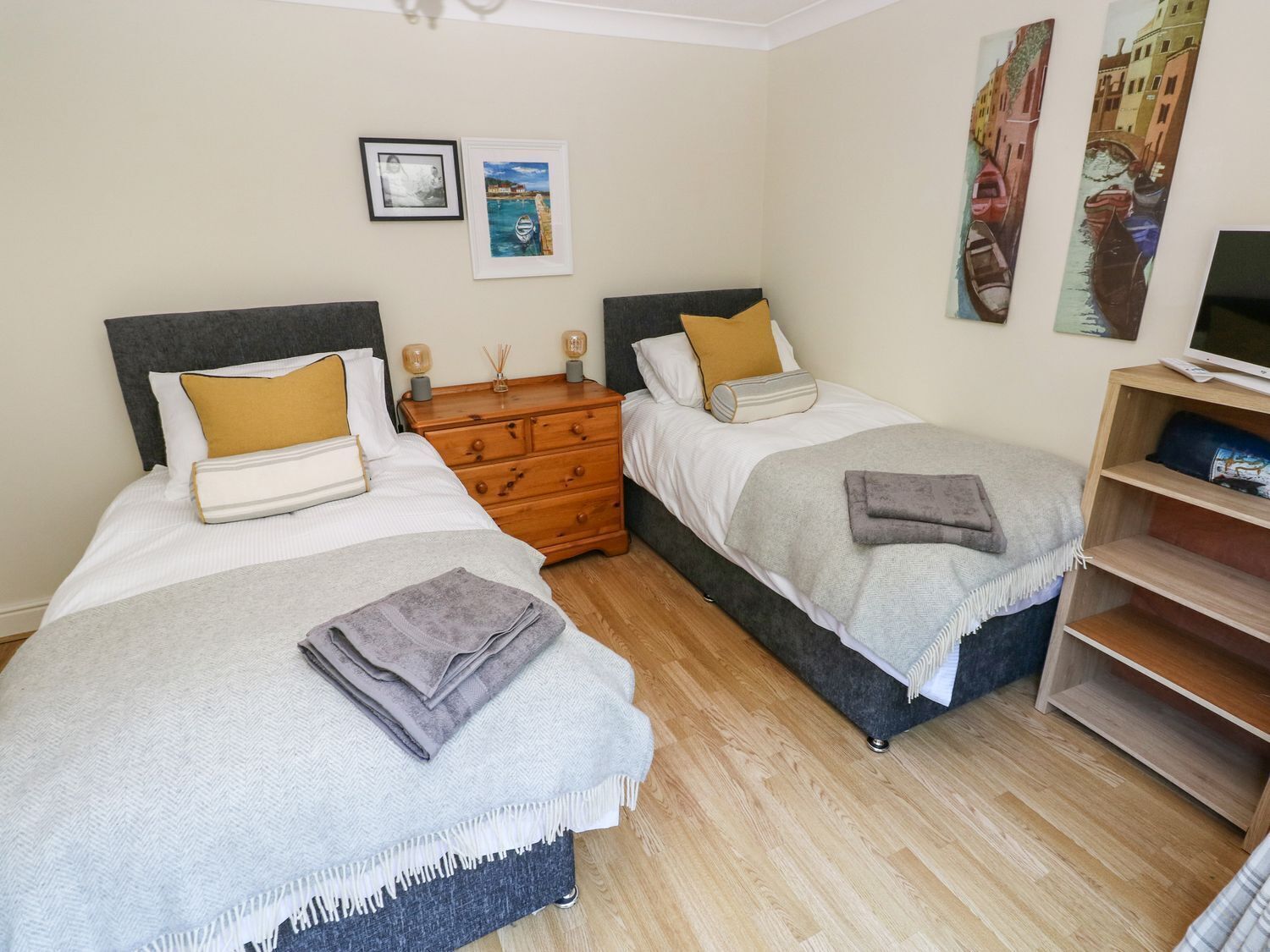 Un dormitorio con dos camas, un aparador de madera y un mueble para televisión.