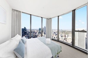 Una habitación de hotel con una cama grande, vistas a la ciudad y una ventana con cortinas.