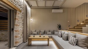 Een moderne woonkamer met een stenen accentmuur, een houten salontafel, een grijze modulaire bank en een trap.