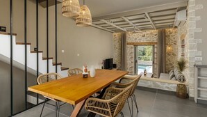 Un espace repas moderne avec une table en bois, des chaises en osier et des luminaires suspendus.