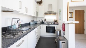 A modern kitchen with white cabinets, a stainless steel range hood, and a built-in oven. - Howells Mere 90, Crows Nest - Elevated Lake Views, Spa Access, Sleeps 4 (Somerford Keynes)