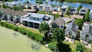 A residential area with modern houses, a river, and a bridge. - Howells Mere 90, Crows Nest - Elevated Lake Views, Spa Access, Sleeps 4 (Somerford Keynes)