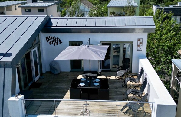 A rooftop patio with a table, chairs, and an umbrella. - Howells Mere 90, Crows Nest - Elevated Lake Views, Spa Access, Sleeps 4 (Somerford Keynes)