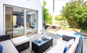 Een moderne buitenruimte met rieten meubels, een jacuzzi en een glazen patio.