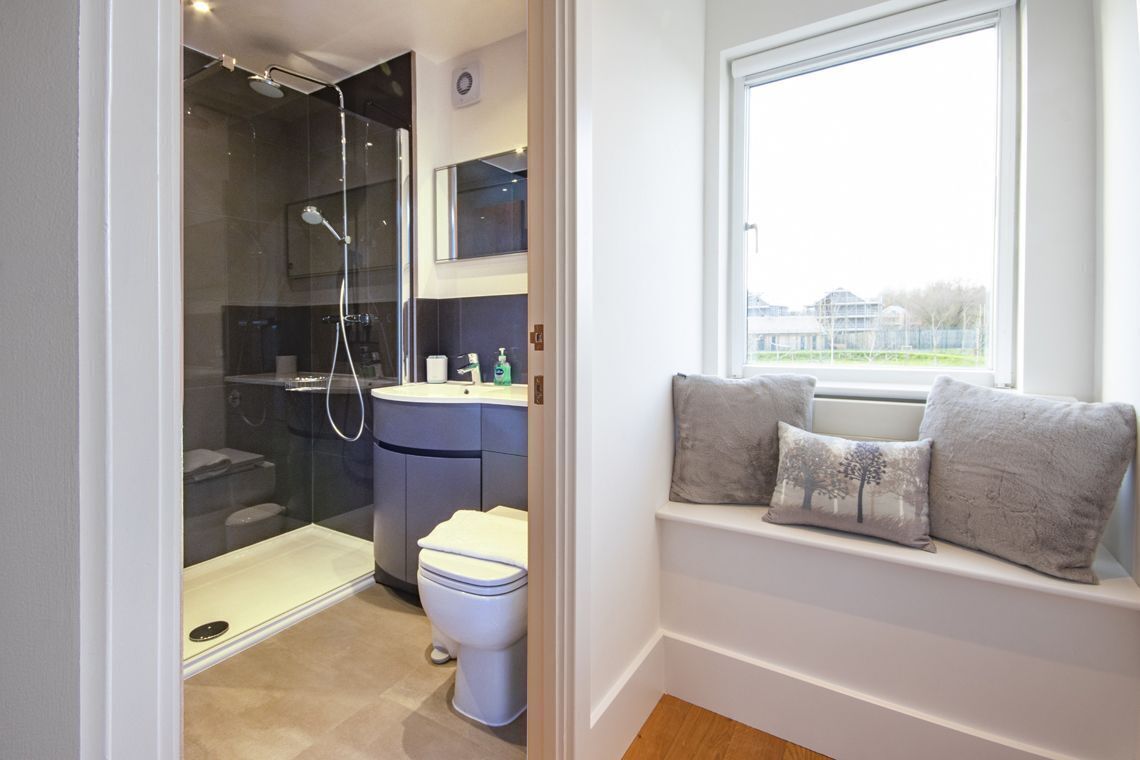Une salle de bain moderne avec une douche à parois de verre, des toilettes blanches et un lavabo.