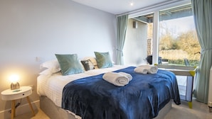 Ein Schlafzimmer mit einem großen Bett, einem Nachttisch und einem Fenster mit Vorhängen.